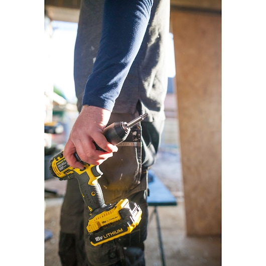 Photo of a person holding a STANLEY FMC625D2 cordless drill with 18V lithium battery, angled view.