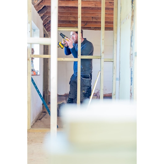 STANLEY FMC625D2 drill used by a worker during house frame construction, indoor setting.