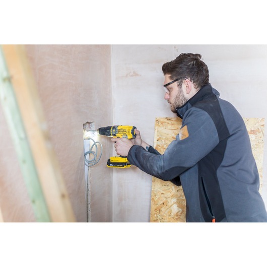 STANLEY FMC626C2K cordless drill being used to drill into wall during construction work.