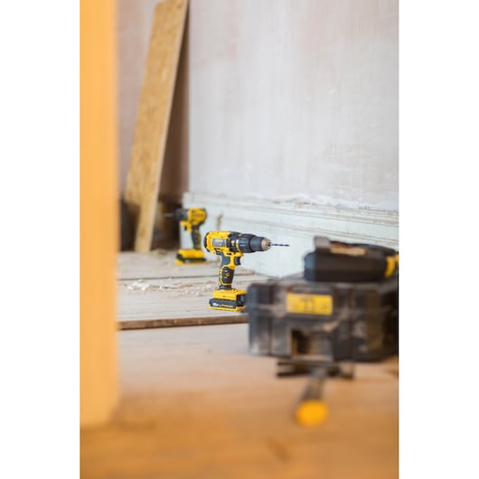 STANLEY FMC626D2K cordless drill driver on floor, yellow and black design, with battery pack, indoor work site.