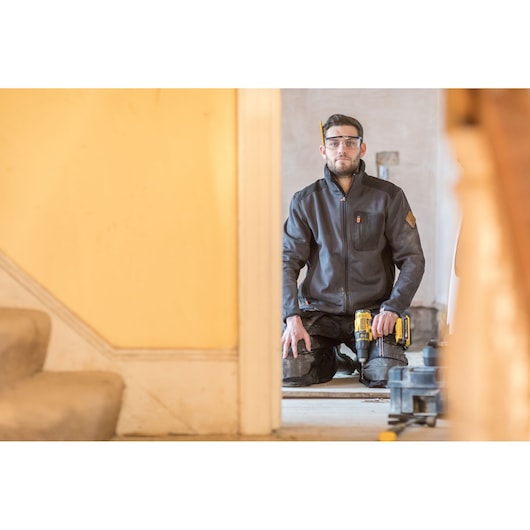 STANLEY FMC626D2K photography of worker kneeling indoors holding yellow drill, construction setting.