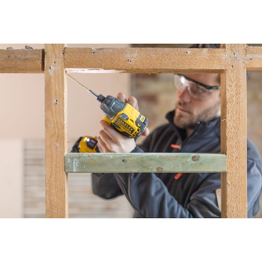 Photo of STANLEY FMC647B impact driver in use on wooden frame, product held by person.