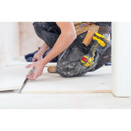 STANLEY FMC647B cordless drill attached to a tool belt during flooring installation, partial side view.
