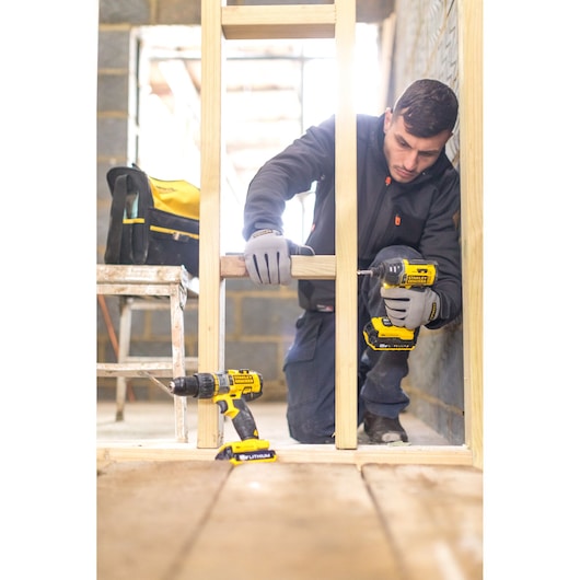 STANLEY FMCK461C2 cordless drill in use at construction site, with yellow and black color design, front view.