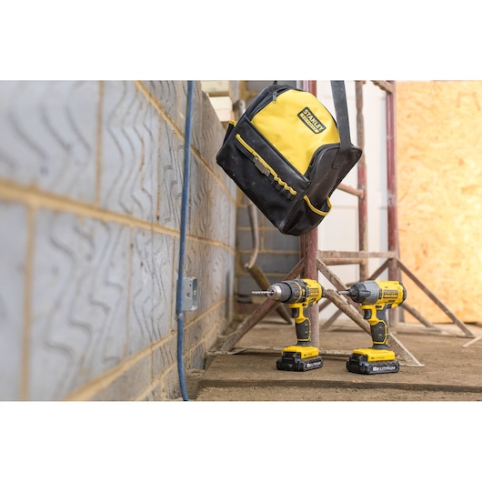 STANLEY FMCK465C2S drill and impact driver set with yellow and black tool bag on construction site floor.