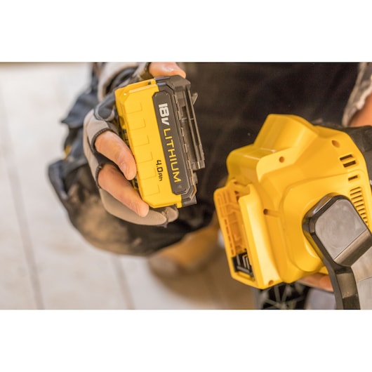 STANLEY FMCL001B 18V lithium battery 4.0Ah hand inserting into yellow power tool, close-up.