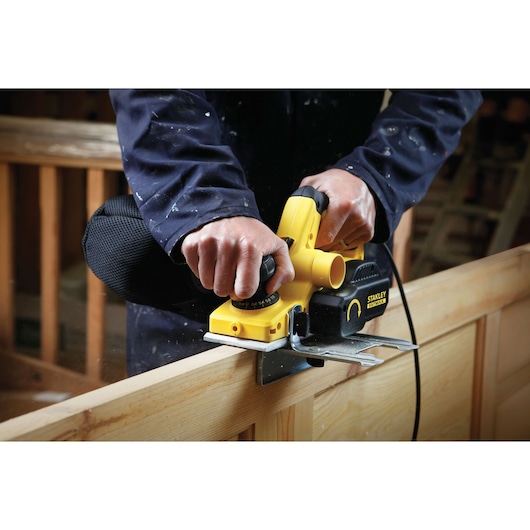 Photo of STANLEY FME630 planer smoothing wood, close-up of tool in use by person in workshop.