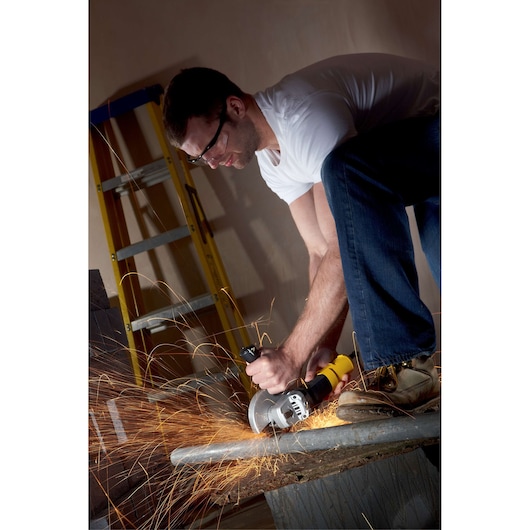 STANLEY FME811K angle grinder cutting metal pipe, sparks flying, with ladder in background.