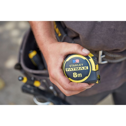 Stanley FMHT0-36327 FatMax 8m tape measure held in hand, yellow and black, close-up view.
