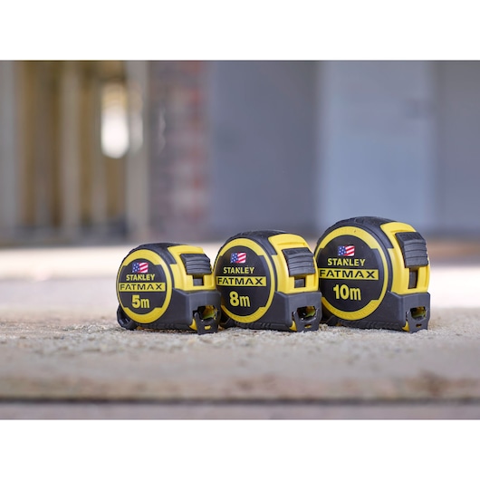 STANLEY FMHT0-36327 tape measures in 5m, 8m, and 10m sizes, yellow and black, on concrete surface.