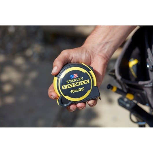 Photo of STANLEY FMHT0-36336 tape measure, yellow and black, held in hand, close-up view.