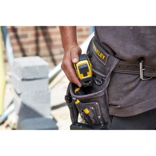 STANLEY FMHT0-36336 tape measure in tool belt pouch, photo on construction site.
