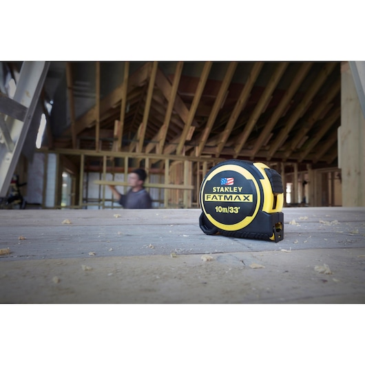 STANLEY FMHT0-36336 FATMAX 10m/33ft tape measure on construction site wooden floor.
