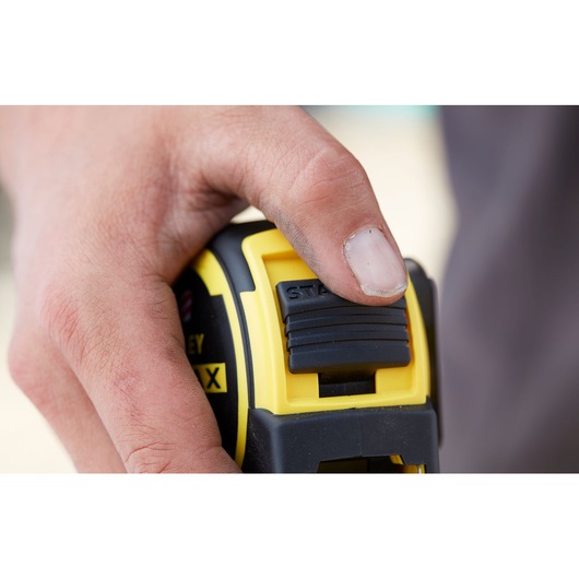 STANLEY FMHT0-36336 tape measure thumb lock detail in use, close-up photography.