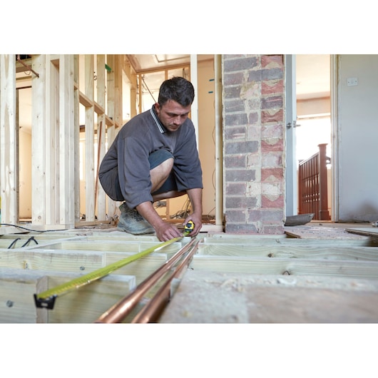 Photo of STANLEY FMHT0-36337 tape measure used to measure copper pipes during house construction.