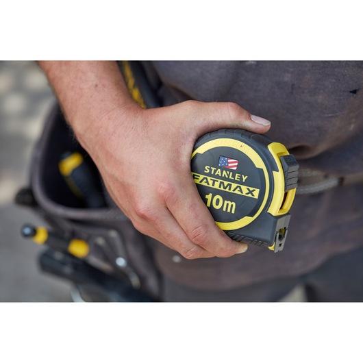 STANLEY FMHT0-36337 FATMAX 10m tape measure held in hand, close-up, yellow and black design.