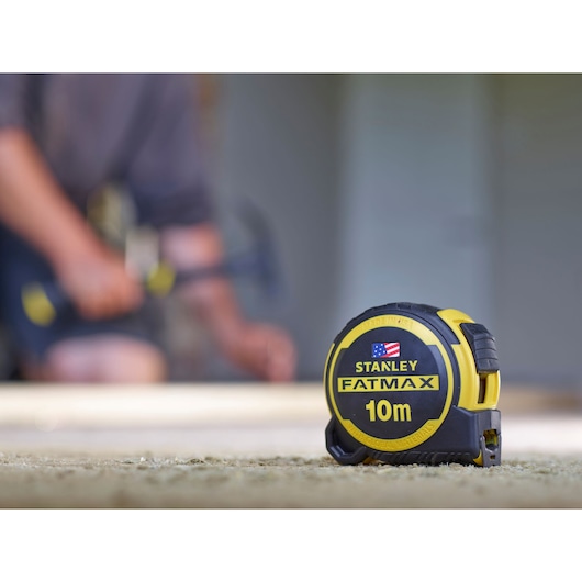 Photo of STANLEY FMHT0-36337 10m FatMax tape measure with black and yellow casing on a work surface.
