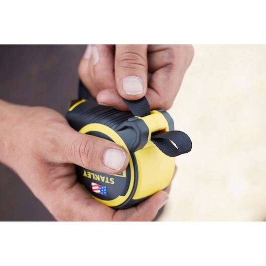 Photo of STANLEY FMHT0-36337 tape measure with black and yellow casing, held by hands, close-up view.