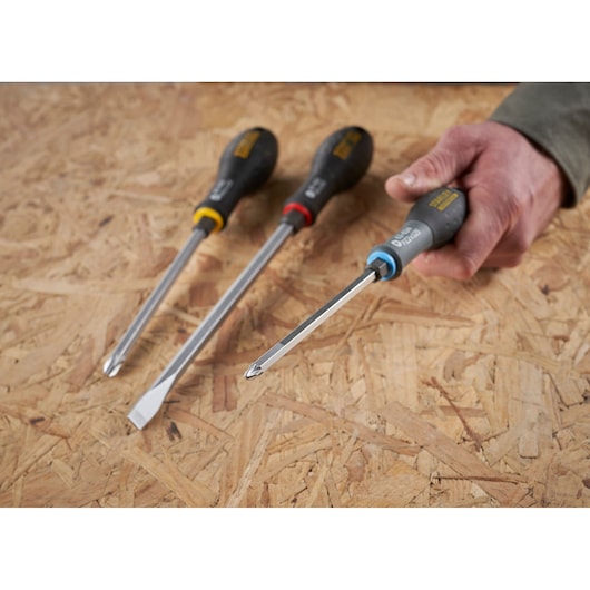 STANLEY FMHT0-62624 screwdriver set with color-coded handles, one held in hand on wooden surface, angled view.