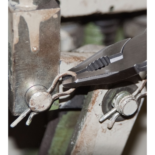 STANLEY FMHT0-72414 pliers gripping wire near metal machinery, close-up photo.