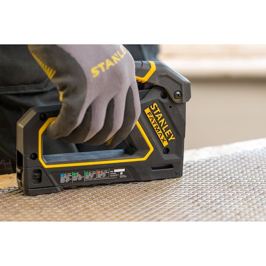Photo of STANLEY FMHT0-80550 FATMAX staple gun in use on metal mesh surface.
