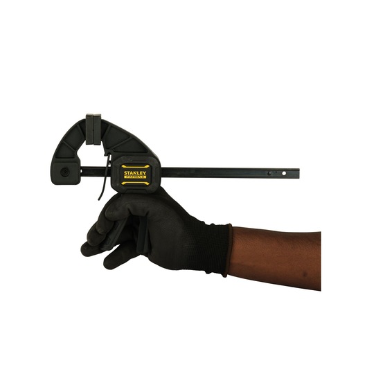 Photo of STANLEY FMHT0-83232 clamp held by a gloved hand, side view, black and yellow handle.