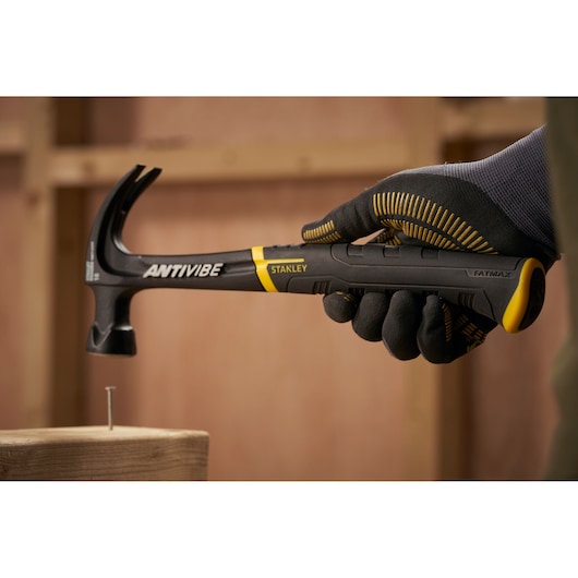 STANLEY FMHT1-51275 claw hammer with black and yellow handle held by gloved hand, FATMAX ANTIVIBE series.