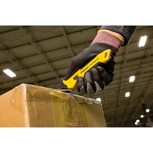 STANLEY FMHT10358-0 utility knife cutting tape on a cardboard box, worker wearing black gloves.