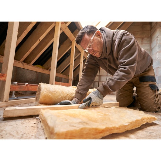 STANLEY FMHT10501-0 utility knife cutting insulation material in attic, close-up photo of tool in use.