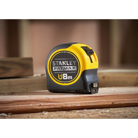Stanley FMHT33869 FatMax magnetic tape measure 8m, yellow and black, side angle, on wood surface.