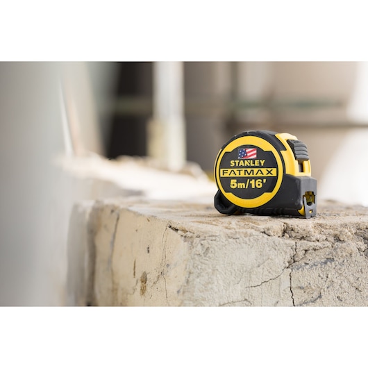 STANLEY FMHT36317-0 tape measure, FATMAX 5m/16ft, yellow and black, on rough concrete surface.