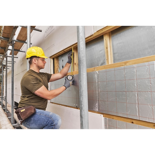 Photo of STANLEY FMHT38215-5 tape measure used on construction wall with insulation panels.