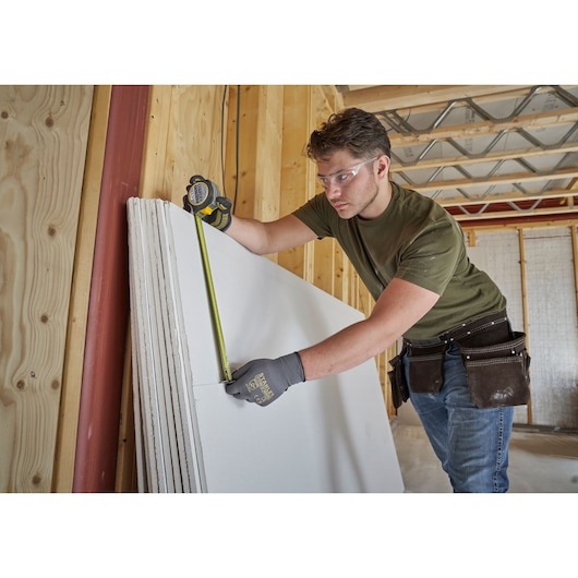 STANLEY FMHT38215-5 tape measure used to measure drywall in construction site.
