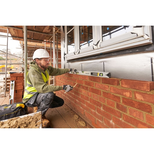 Photo of STANLEY FMHT43674-1 spirit level used by a construction worker on a brick wall at a building site.