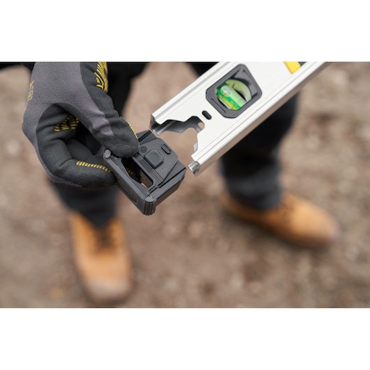 STANLEY FMHT43676-1 spirit level accessory held in gloved hand, close-up outdoor angle.