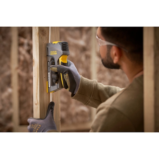 STANLEY FMHT6-70868 staple gun in use on wooden frame, close-up photography of tool and gloved hand.