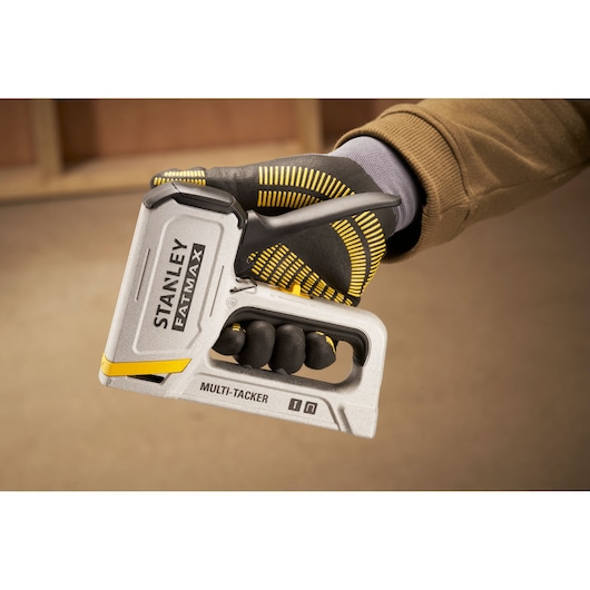 STANLEY FMHT70443-0 hand-held silver multi-tacker tool being gripped by a gloved hand.