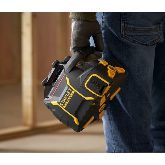 Photo of STANLEY FMHT77446-1 portable laser level held by gloved hand, black and yellow design.