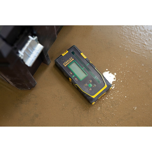 STANLEY FMHT77653-0 electronic detector in black and yellow on wet brown floor, top angle.