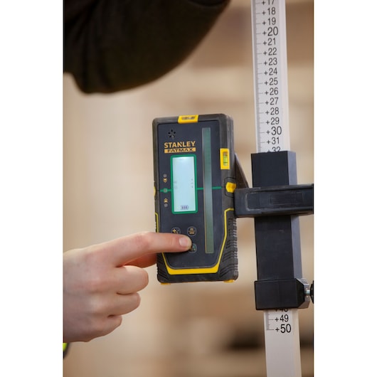 STANLEY FMHT77653-0 laser detector held by hand, attached to measuring rod, close-up photography.