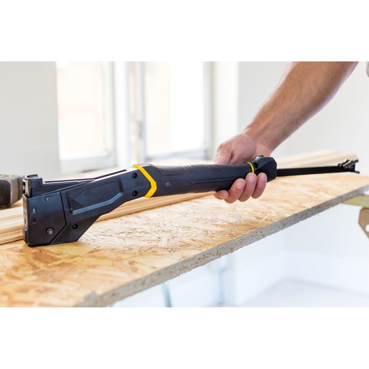 STANLEY FMHT81394-9 hand saw with black and yellow accents, held on a wooden board in a construction setting.
