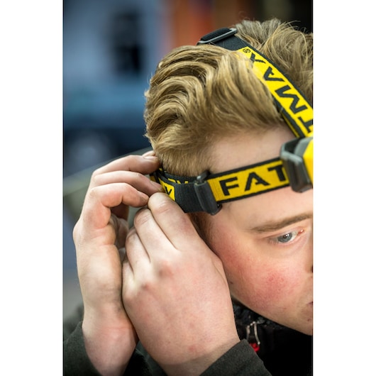 Photo of STANLEY FMHT81509-0 headlamp being adjusted by hand, yellow logo on black headband.