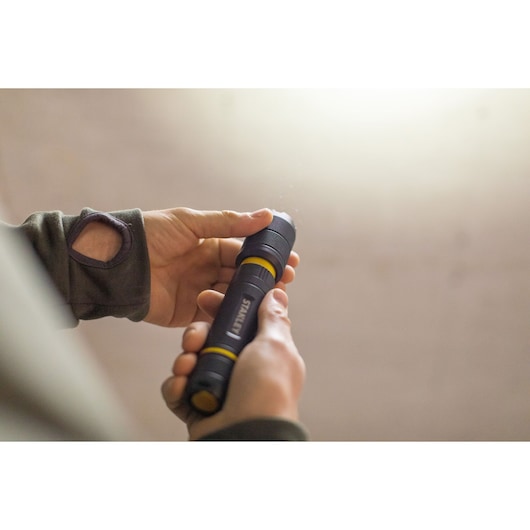 Photo of STANLEY FMHT81511-0 black and yellow flashlight being held in hand.