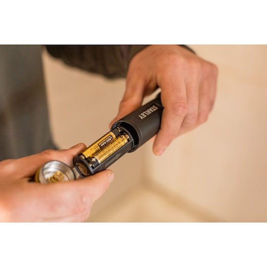 STANLEY FMHT81511-0 flashlight with batteries being inserted, close-up photography.