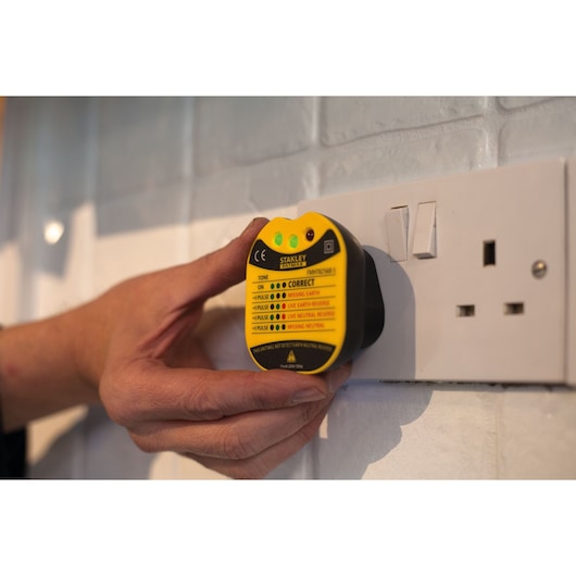 STANLEY FMHT82568-5 socket tester handheld, plugged into wall outlet, close-up photo.