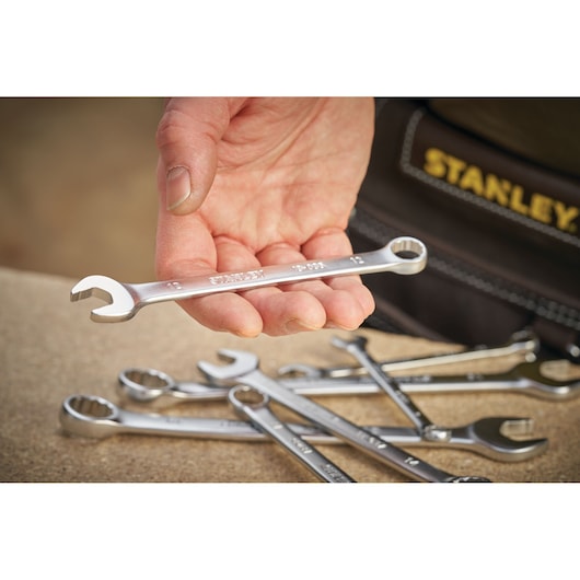Stanley FMMT13029-0 combination wrench held in hand with other wrenches on table, photography close-up.