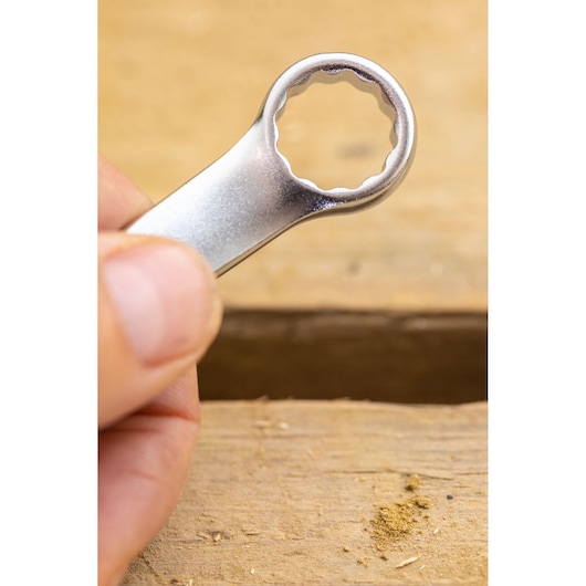 STANLEY FMMT13038-0 box-end wrench in hand, close-up view, photographed on a wooden surface.