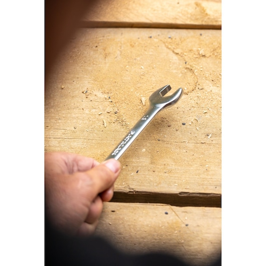 STANLEY FMMT13042-0 wrench held by hand on wooden surface, silver finish, photography side angle.