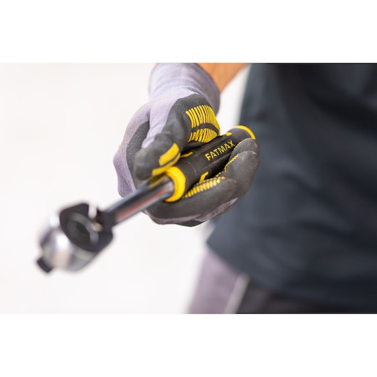 STANLEY FMMT82677-0 ratchet wrench with yellow and black handle held by gloved hand, close-up photography.