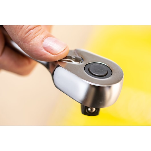 Close-up photo of STANLEY FMMT82677-0 ratchet handle with thumb pressing the release button.